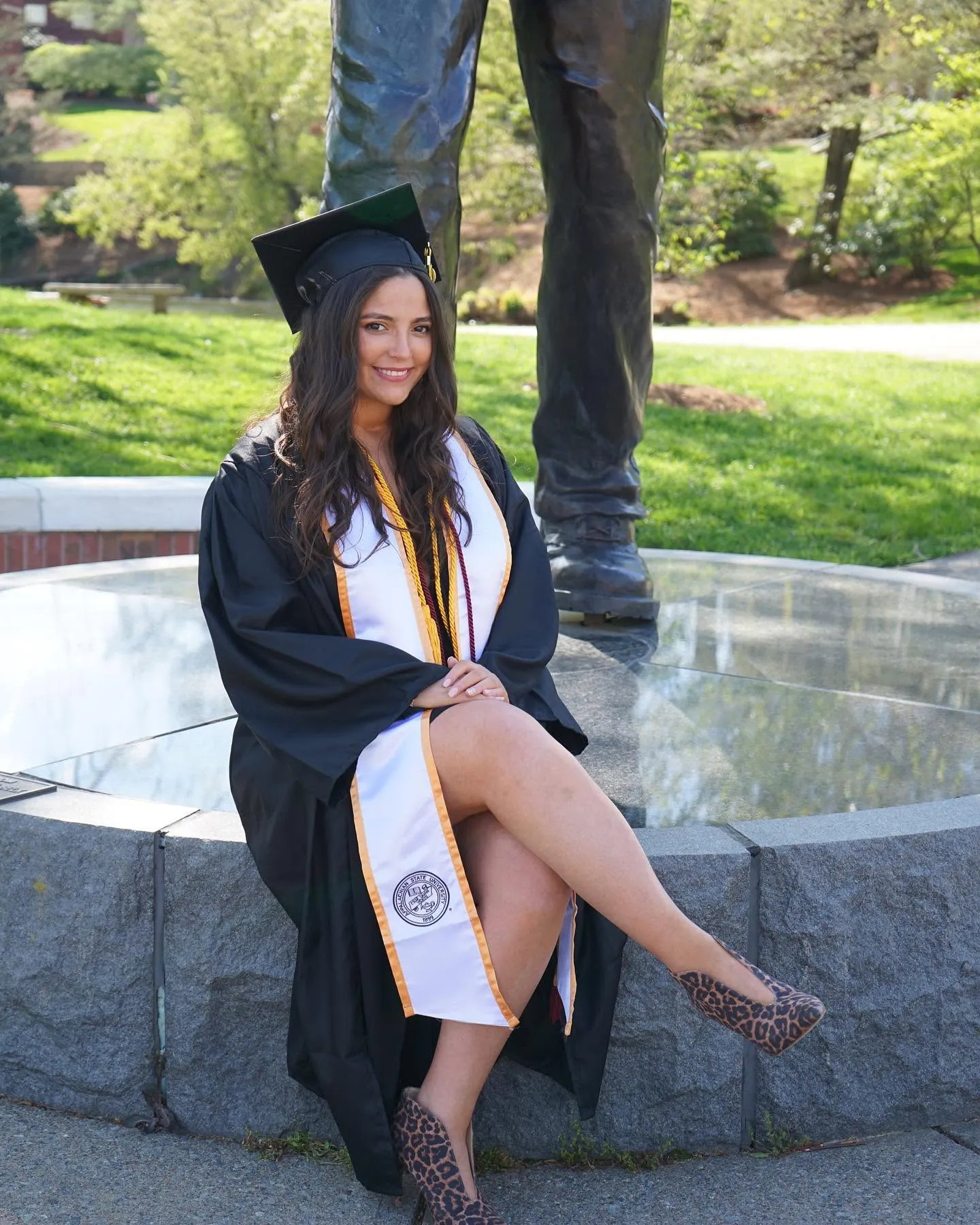 Ashley Art in her graduation cap and gown, seated outdoors.